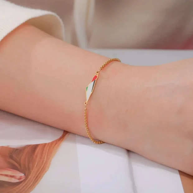 Bracelet doré ajustable avec pendentif carte de Palestine colorée porté au poignet